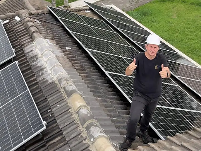 Técnico da LS, empresa de energia solar e segurança eletrônica, em telhado com painéis solares instalados
