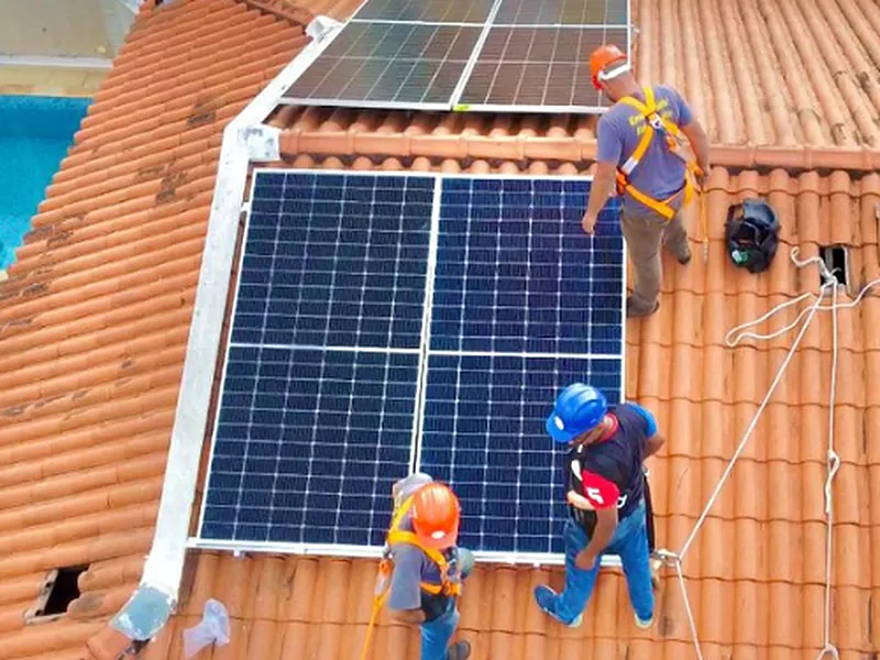 Equipe da LS com EPI e cinto de segurança instalando painéis solares em telhado